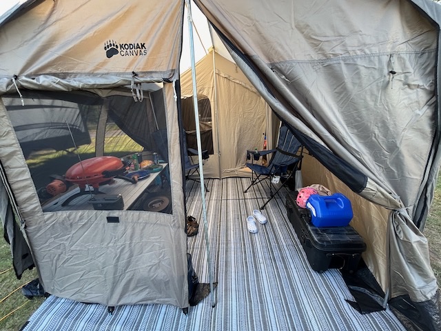 Canvas tent entrance with dry gear organized under cover