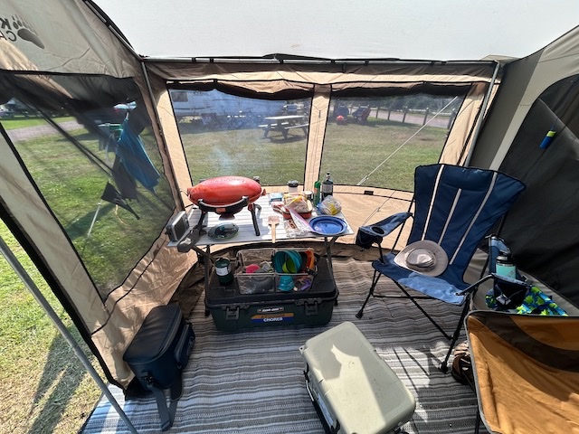 Covered camp kitchen with cooking gear and storage totes