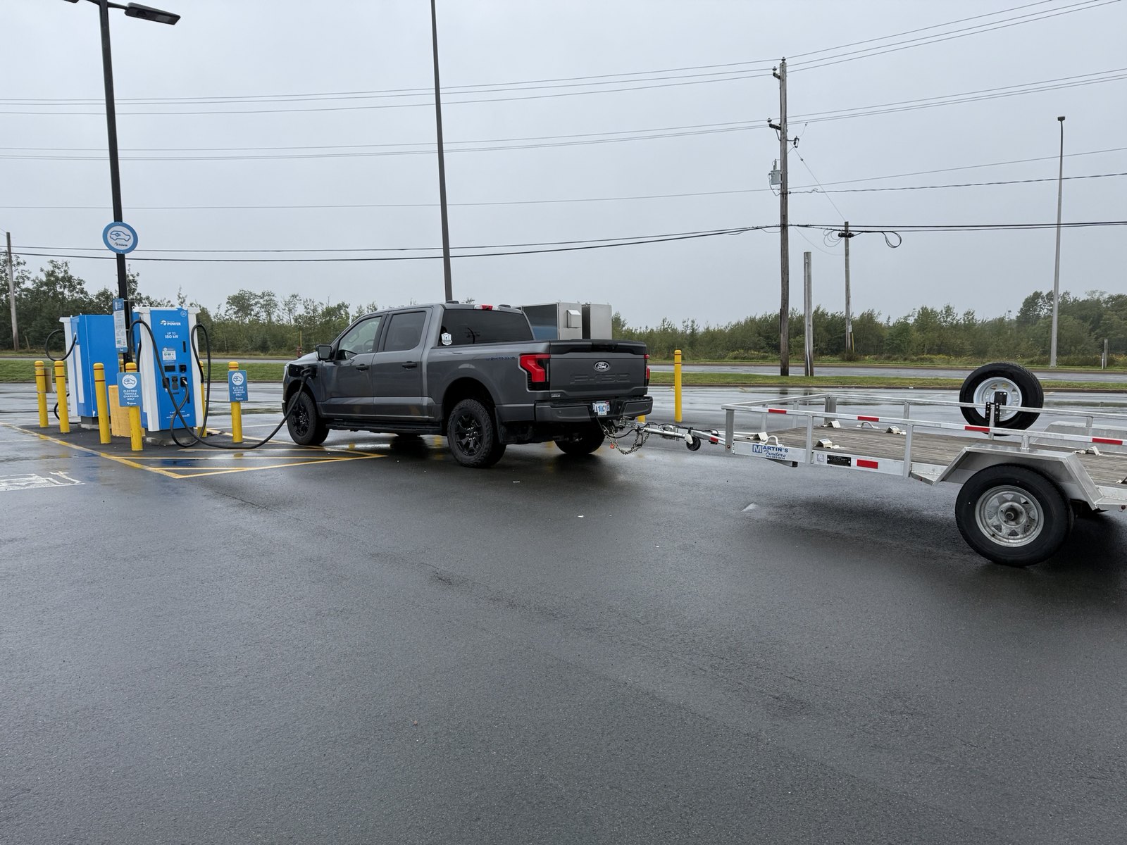 Ford F-150 Lightning charging in the Truro area with an open utility trailer attached
